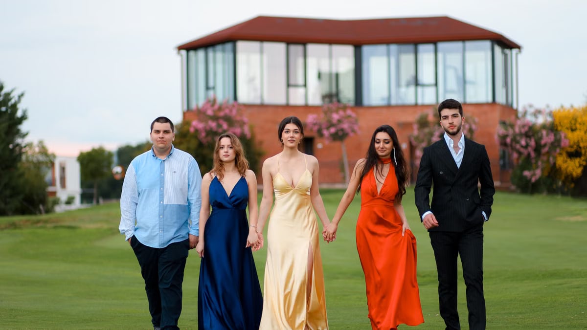A fashionable group of young men and women walking on a lawn in elegant attire, showcasing style and connection.