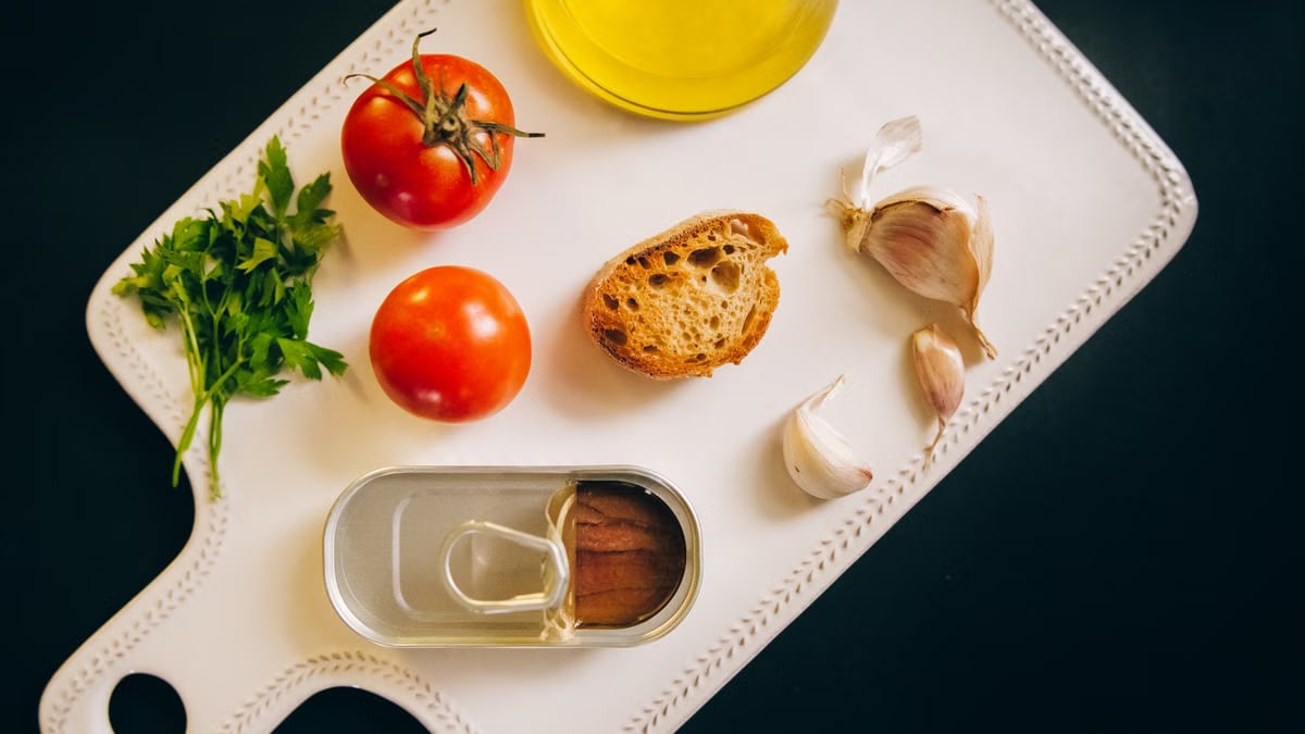 Fresh ingredients for making Catalán toast, including tomatoes, anchovies, and garlic.